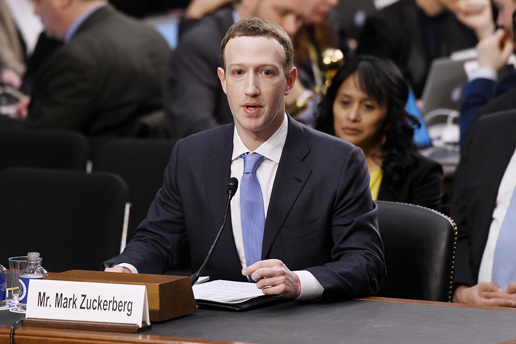 Facebook CEO Mark Zuckerberg wears a dark suit, white shirt, and blue tie.