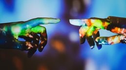 Human hand reaching for robotic hand with outer space image projected on it - stock photo