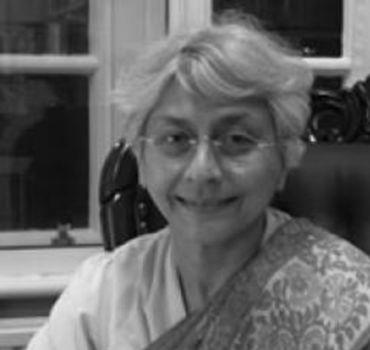 Portrait photograph of Professor Aditi Lahiri, an Indian lady with short grey hair and glasses, wearing a sari.