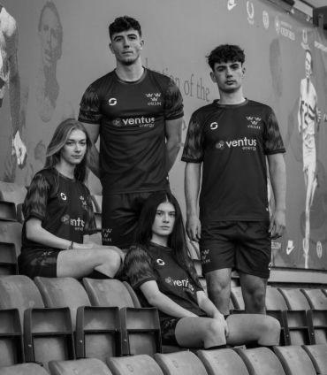 Four men and women Blues team members including Women’s Blues co-captains, Men’s Blues captain and other Men's squad member sat in the stands in their new kit